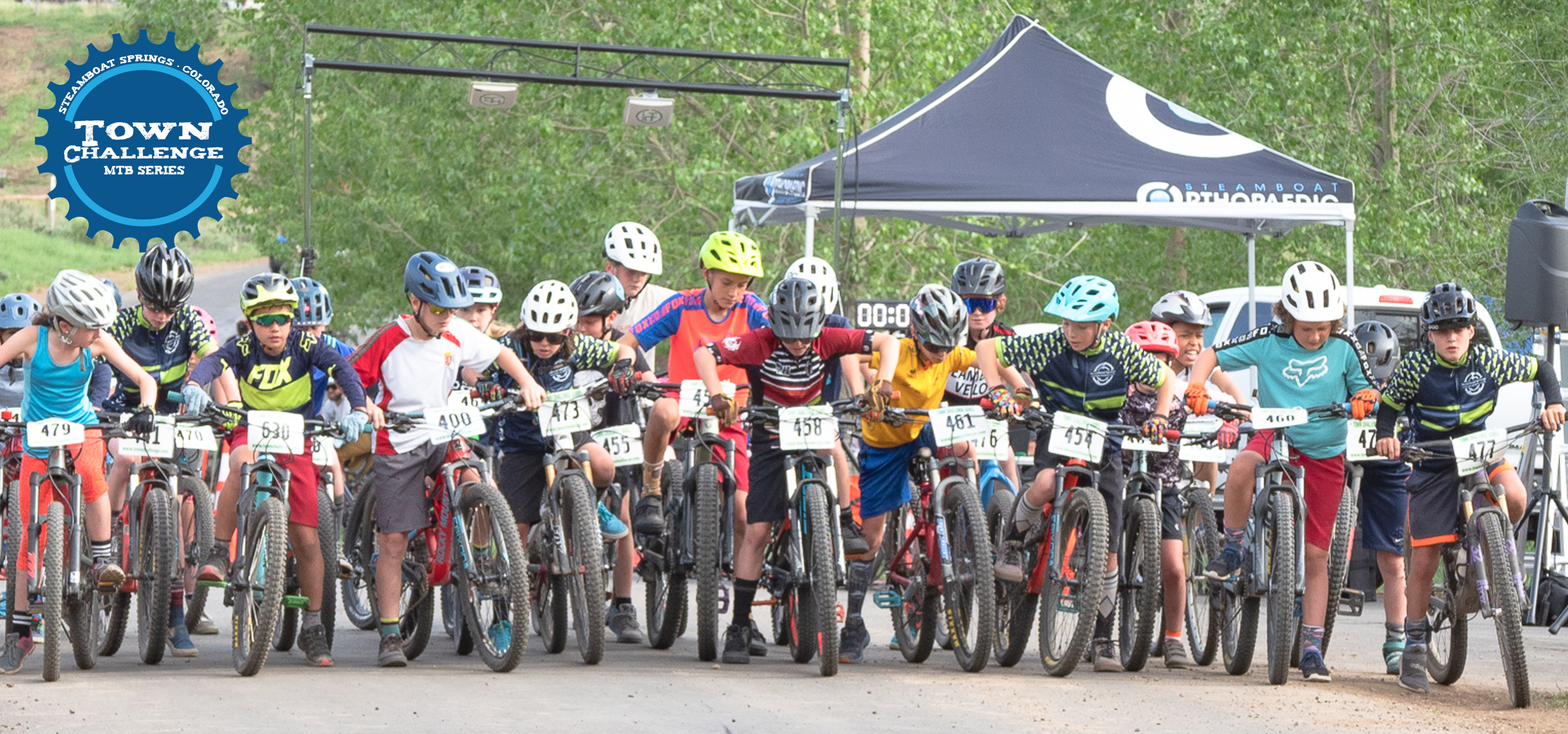 Youth racers lined up at the start line of a Town Challenge mountain bike race. 